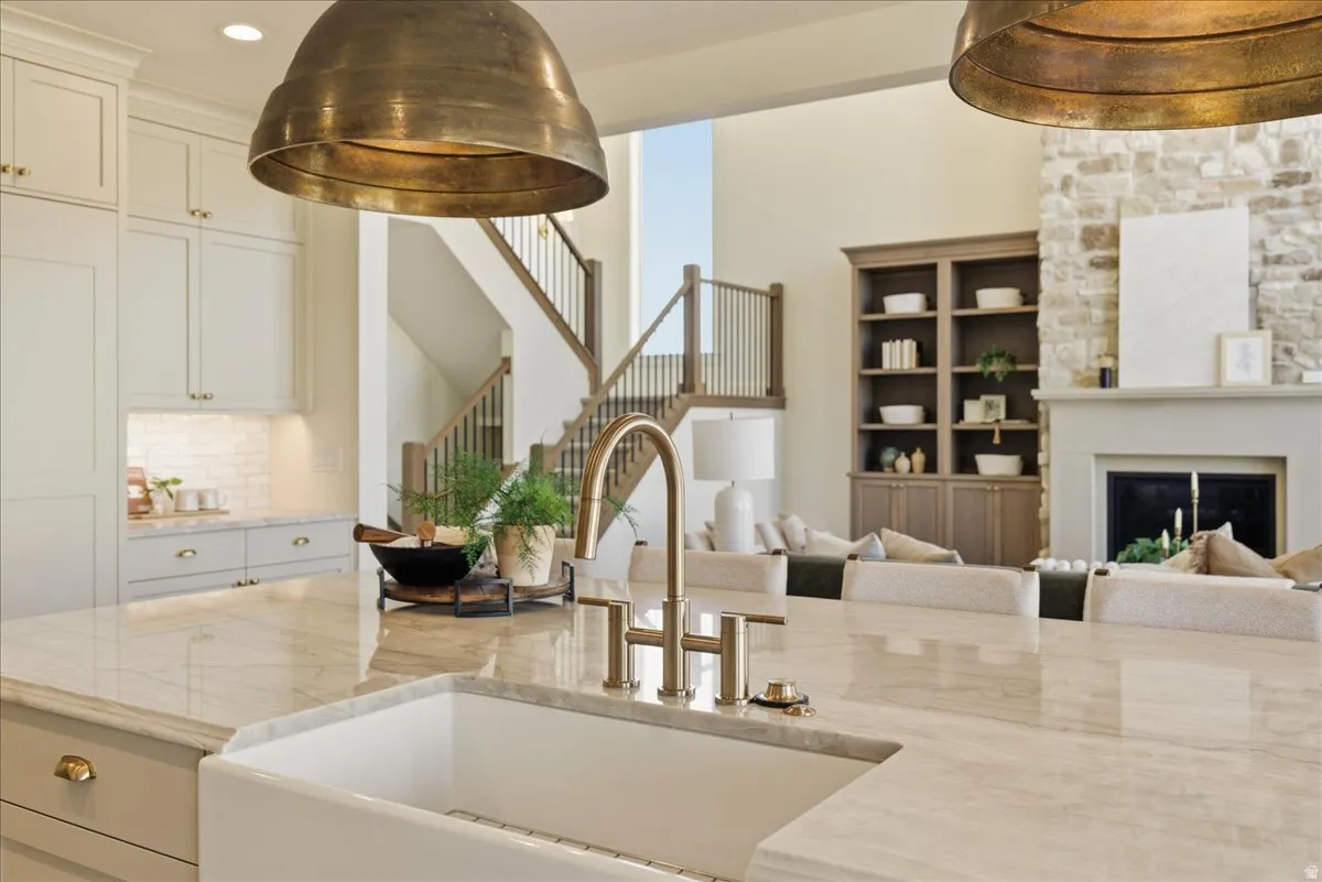 Gourmet kitchen island featuring a farmhouse sink and polished brass faucet, complemented by light cabinetry and a white subway tile backsplash