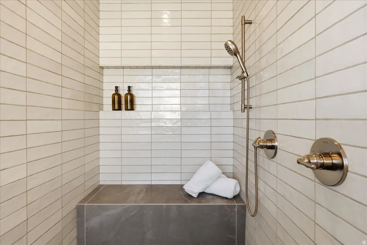 Shower stall featuring horizontal white tile, built-in bench, integrated shower niche, and brushed nickel fixtures