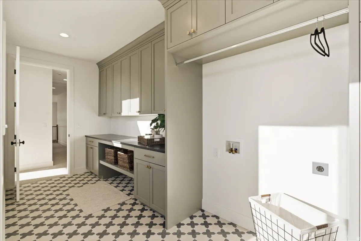 Utility room featuring patterned tile flooring, custom cabinetry, dark countertops, and a built-in hanging rod