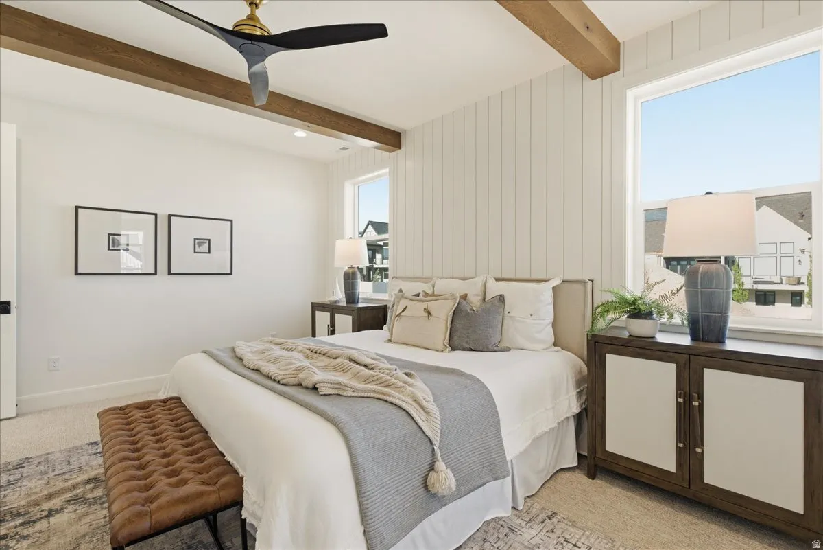 Bedroom featuring a decorative wall panel, two large windows, wood-finish ceiling beams, an overhead ceiling fan, and recessed lighting