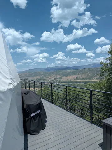 Outdoor decking with black metal railing, offering expansive mountain and valley scenery
