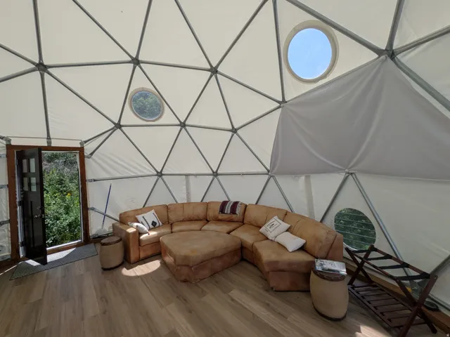 Geodesic dome interior featuring a sturdy metal framework, white fabric panels, and wood-finish flooring