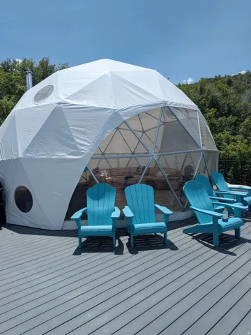 Geodesic dome structure featuring a partial transparent facade, circular window, and a metal flue
