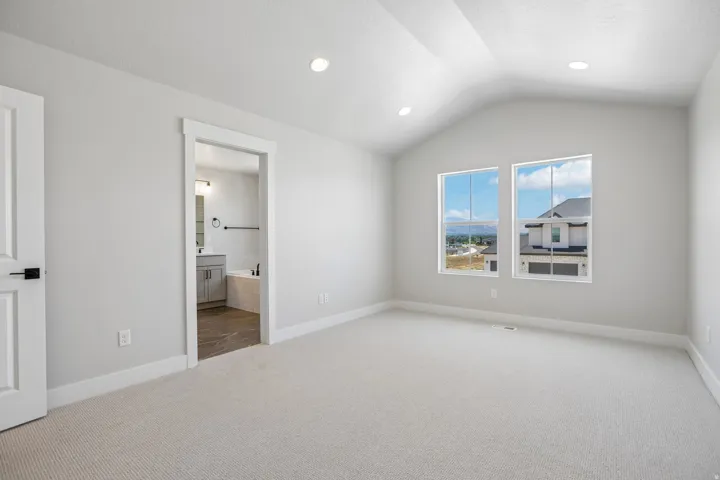 Vaulted ceiling room with two double-hung windows, recessed lighting, and light-colored carpeting