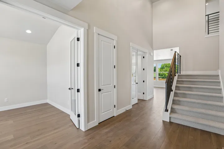 Spacious foyer with wood-finish flooring, a carpeted staircase, and an open-concept design featuring high ceilings