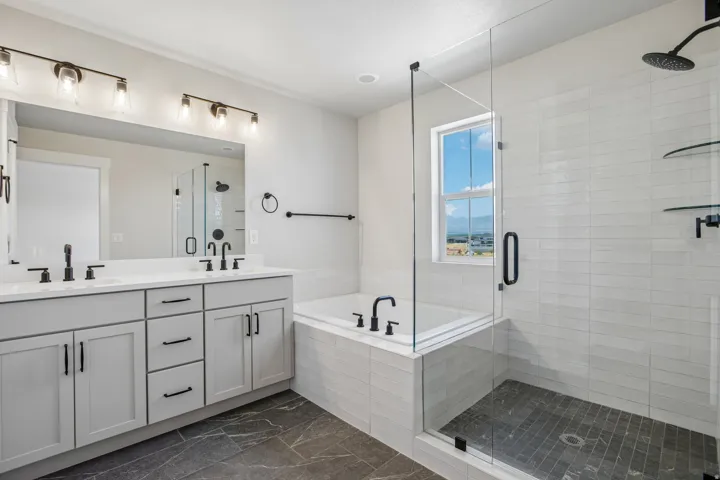 Contemporary bathroom featuring a spacious glass-enclosed shower with a rainfall showerhead, a separate soaking tub, and a dual vanity with light gray cabinetry and matte black hardware
