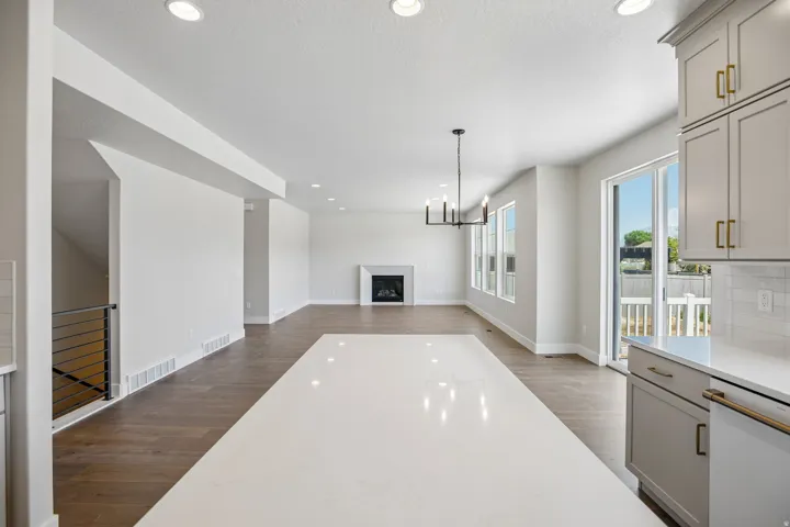 Spacious open-concept living area featuring a large kitchen island with a white countertop, wood-finish flooring, a fireplace, and recessed lighting