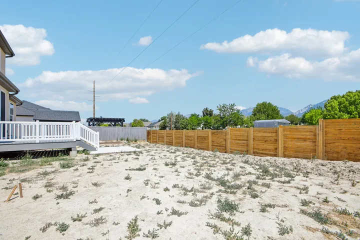 Spacious backyard featuring a newly installed wooden privacy fence, a concrete patio, and a composite deck with white railings