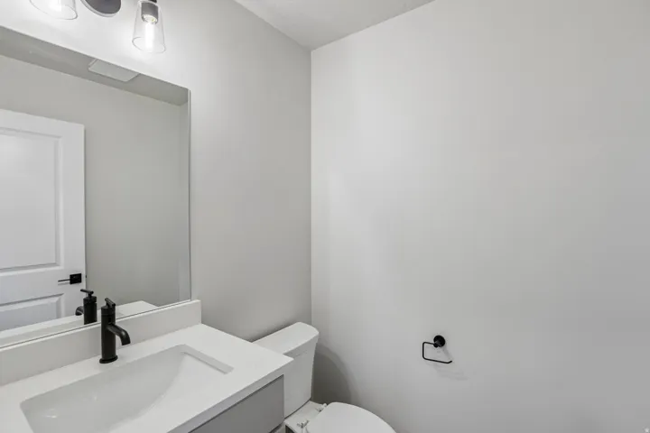 Powder room featuring a white vanity with integrated sink, matte black faucet, and a wall-mounted mirror