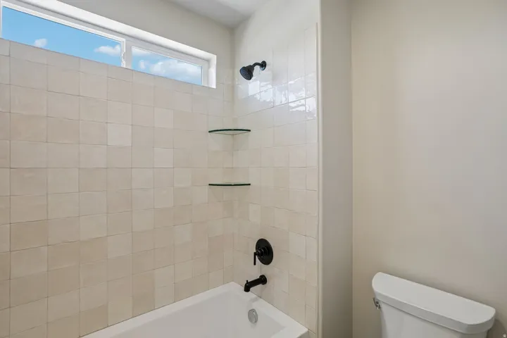 Bathtub and shower combination featuring floor-to-ceiling square tile surround