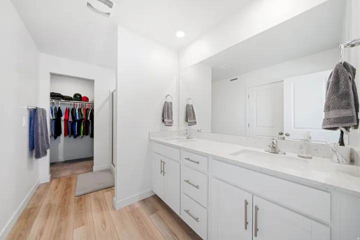 Bathroom featuring a dual vanity with white cabinetry, light-colored countertops, and undermount sinks