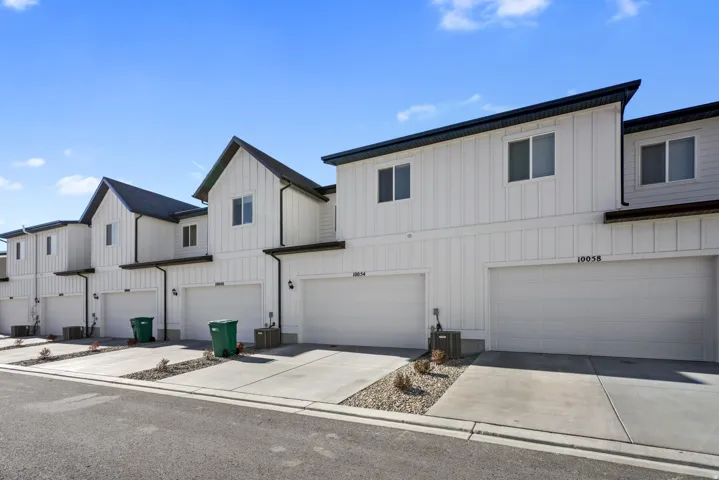 Modern townhome exterior featuring white vertical siding and dark trim