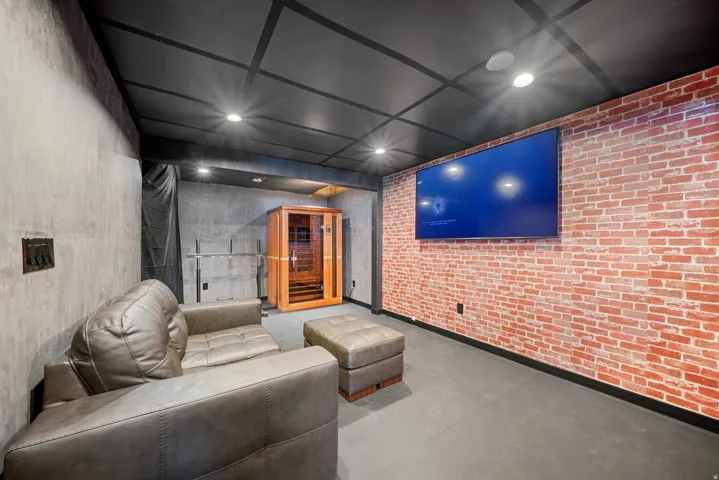 Entertainment area featuring an exposed brick accent wall with a wall-mounted display
