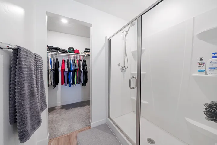 Walk-in shower with clear glass enclosure and integrated shelving, featuring chrome fixtures