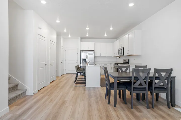 Open-concept living area with wood-finish flooring, recessed lighting, and a white color palette