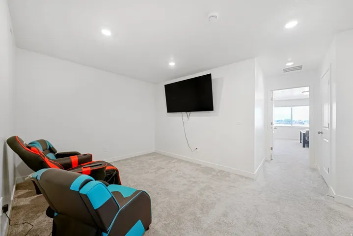 Carpeted secondary room featuring a wall-mounted television, recessed lighting, white walls, and white trim