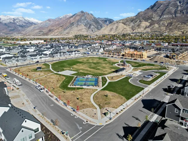 Community green space featuring a large lawn area, paved pathways, and an enclosed sports court