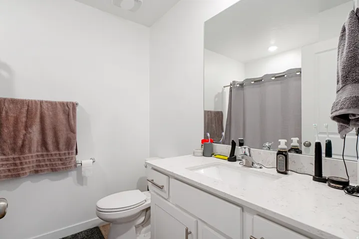 Bathroom featuring a single vanity with an integrated sink, a light-toned countertop, and white cabinetry with brushed nickel hardware
