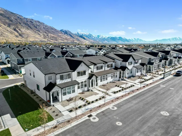 Modern residential development featuring a row of multi-story homes with dark pitched roofs and white siding