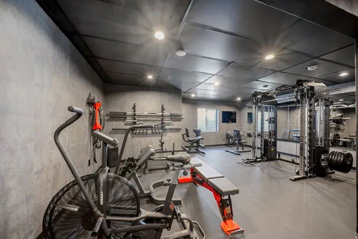Dedicated fitness space featuring textured wall finishes, recessed lighting, and rubberized flooring