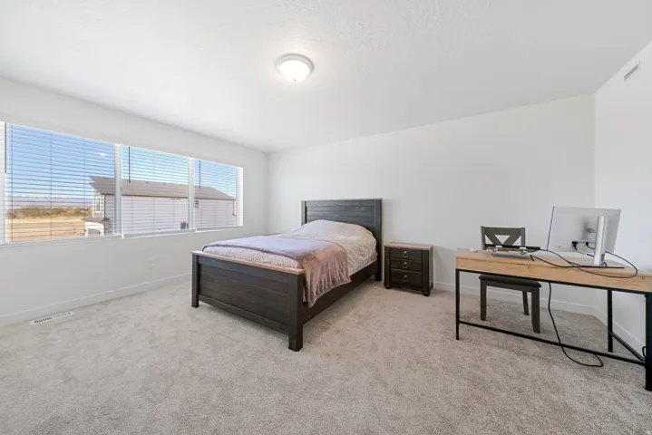 Spacious room featuring multiple horizontal windows with blinds, light-colored carpet flooring, and a flush-mount ceiling light fixture