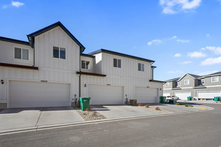 Modern townhome exterior featuring vertical white siding with dark trim accents