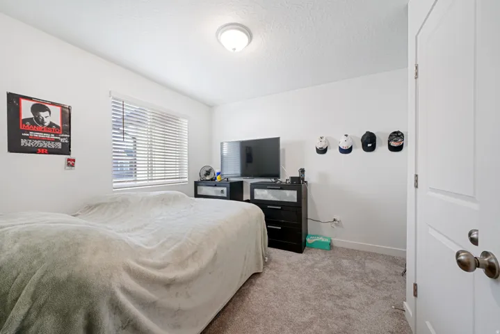 Carpeted bedroom with a single window featuring horizontal blinds