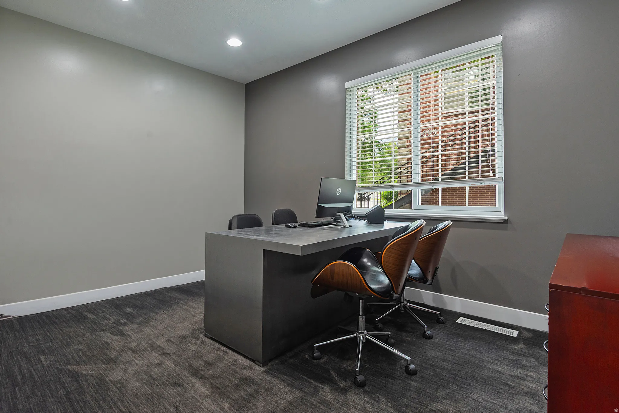 Room featuring recessed lighting, a window with horizontal blinds, and a built-in desk with a dark finish