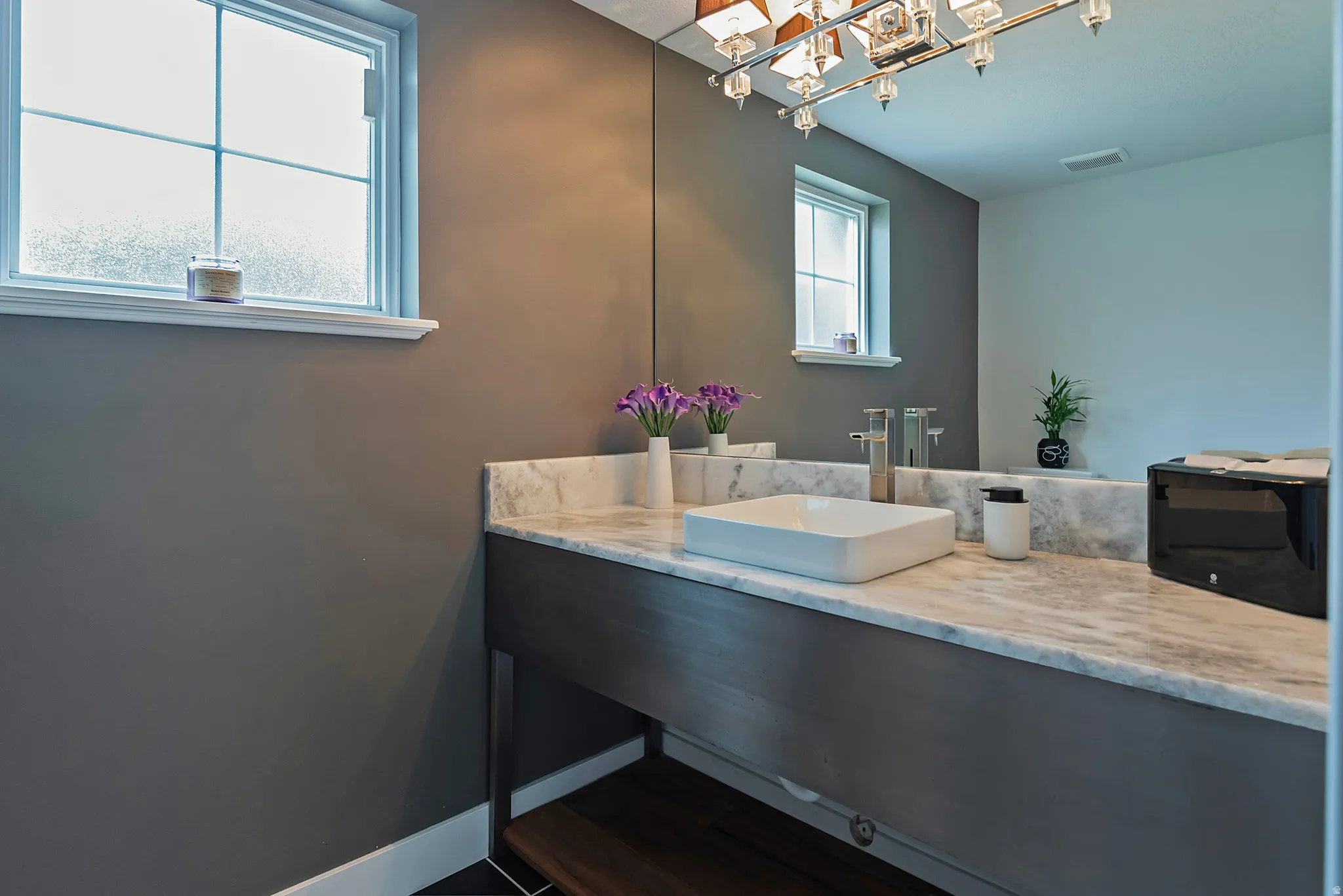 Bathroom vanity featuring a rectangular vessel sink, dual chrome faucets, and stone countertop