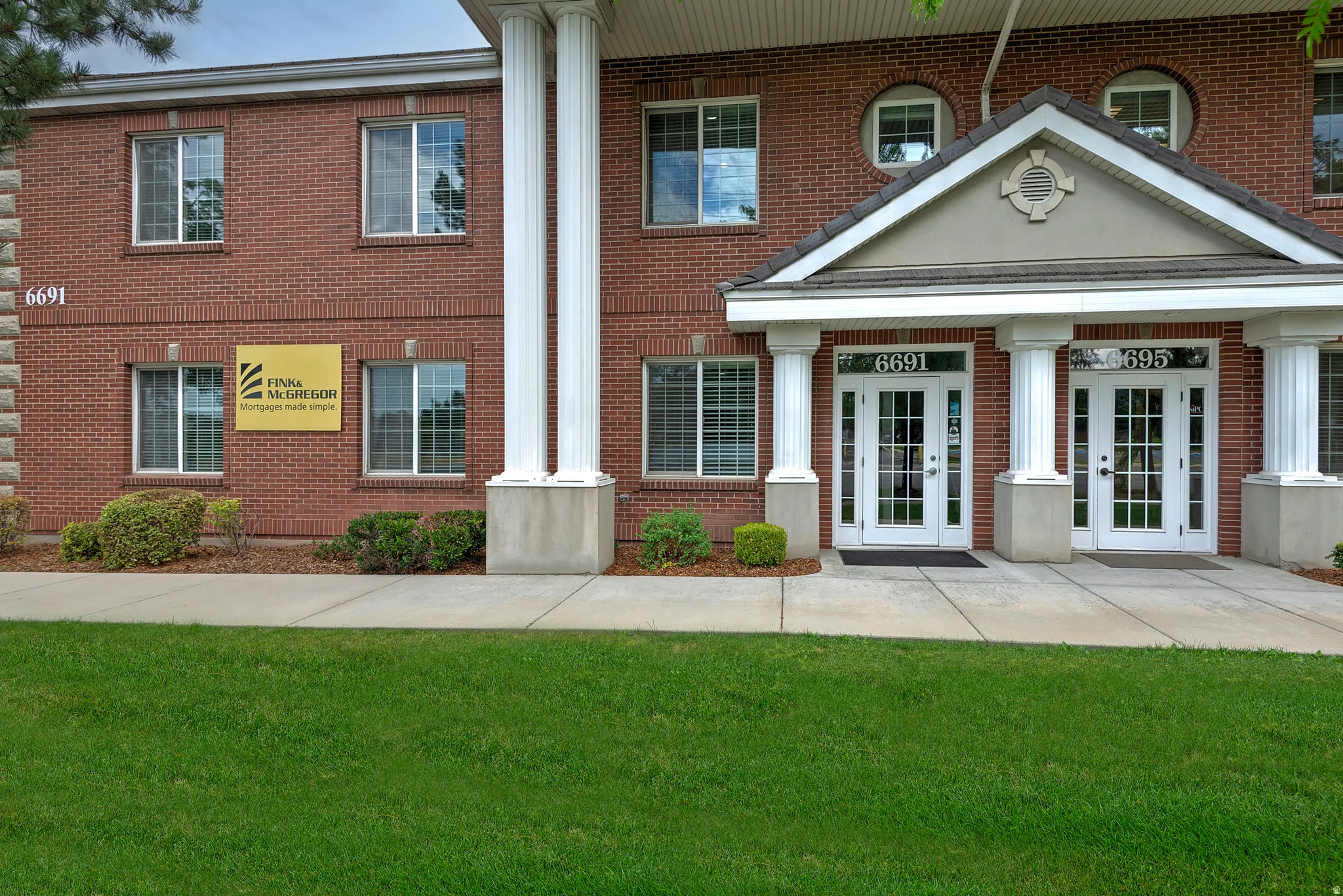 Brick exterior with white window frames and a prominent entry portico