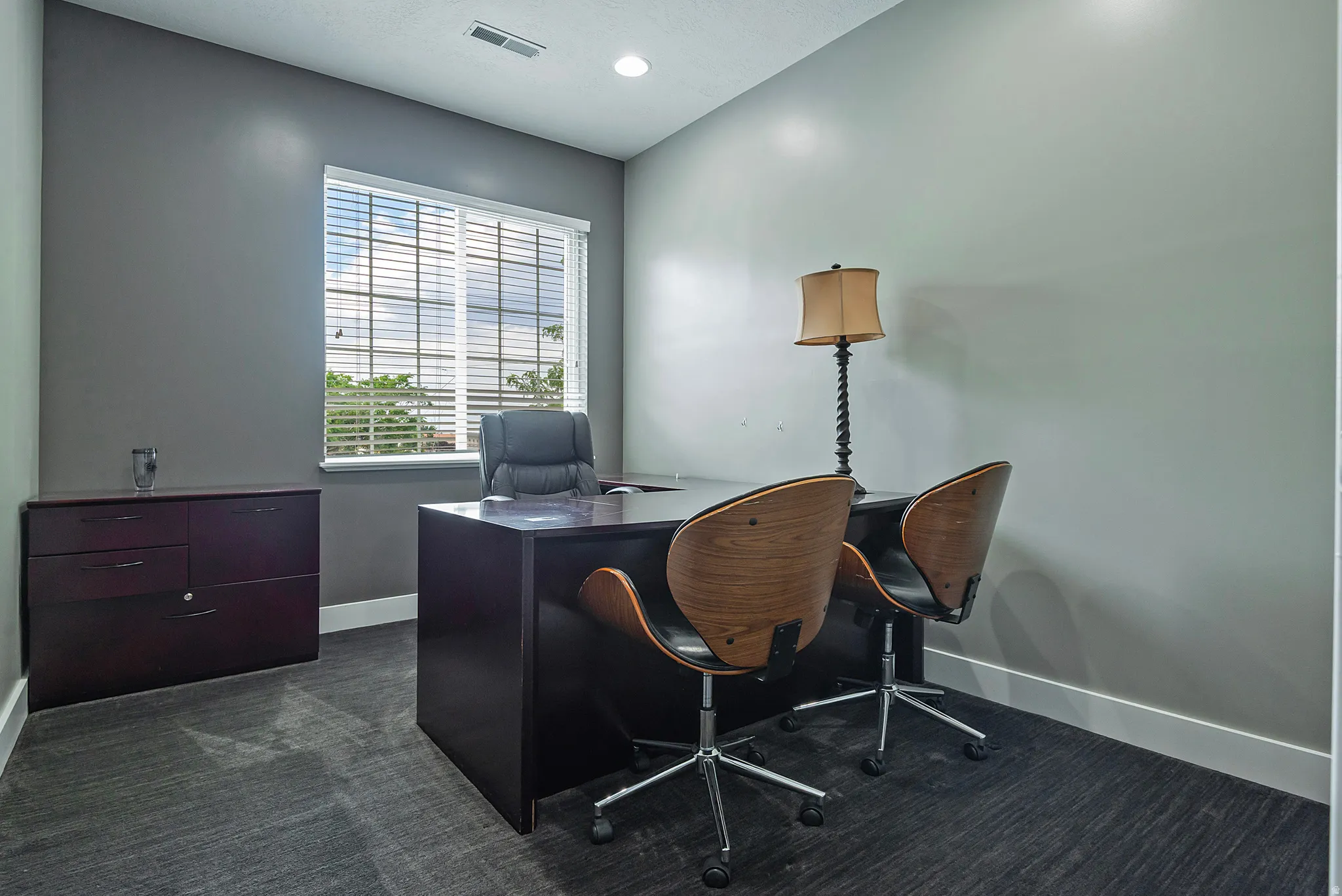 Room featuring a large window with horizontal blinds, grey textured carpeting, and white baseboards
