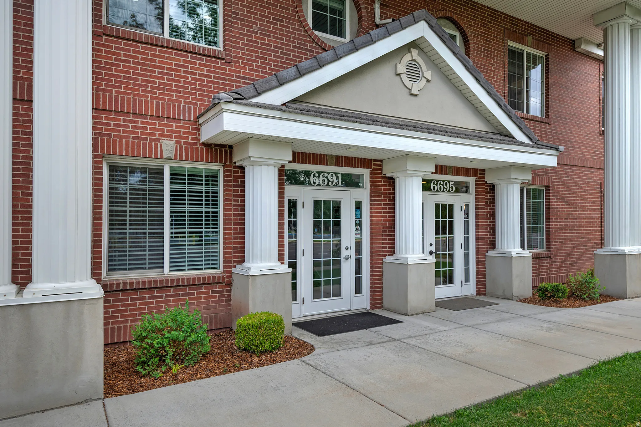 Brick exterior featuring a portico entry with white fluted columns and a gabled roofline