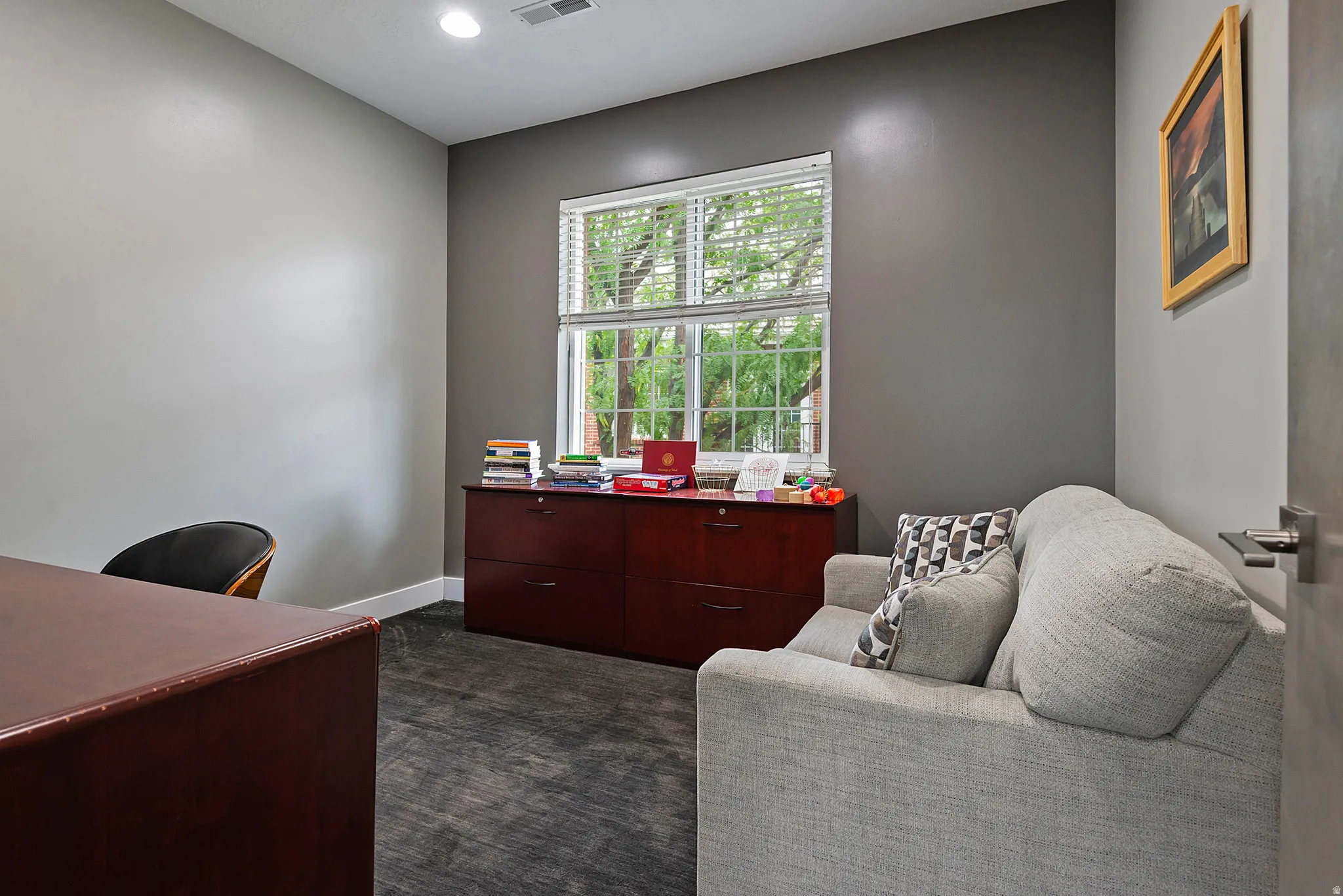Interior room featuring a large window with white blinds, dark gray and light gray walls, dark wood-finish cabinetry, and recessed lighting