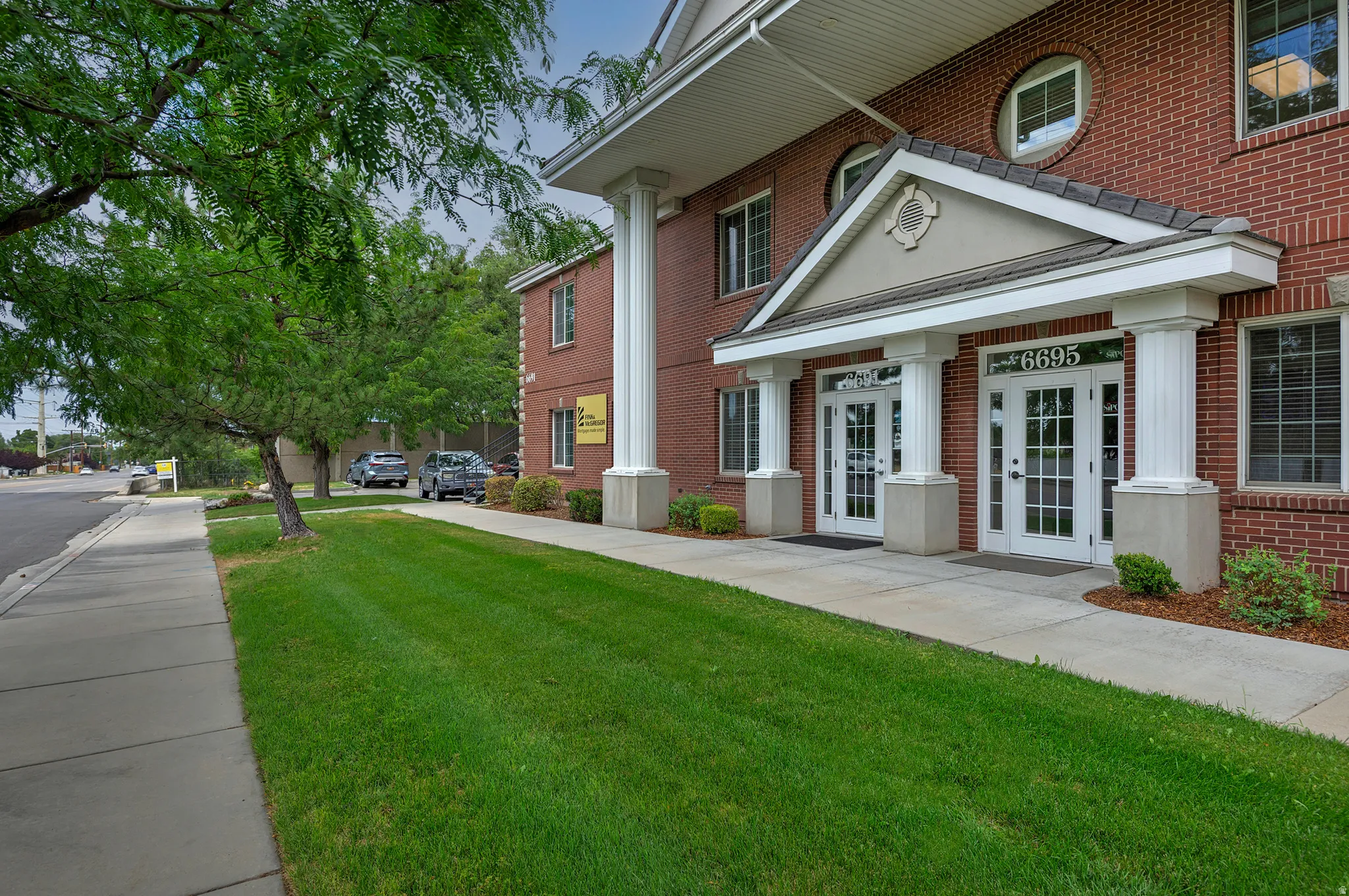 Brick exterior featuring two prominent entryways with white doors, transom windows, and overhead porticos supported by decorative columns