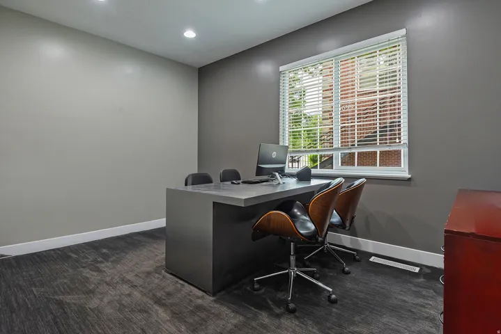 Room featuring recessed lighting, a window with horizontal blinds, and a built-in desk with a dark finish