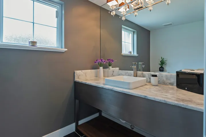 Bathroom vanity featuring a rectangular vessel sink, dual chrome faucets, and stone countertop