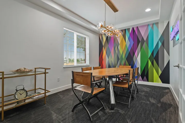 Feature wall with a geometric pattern, contemporary chandelier, recessed lighting, carpet flooring, and a single window with blinds