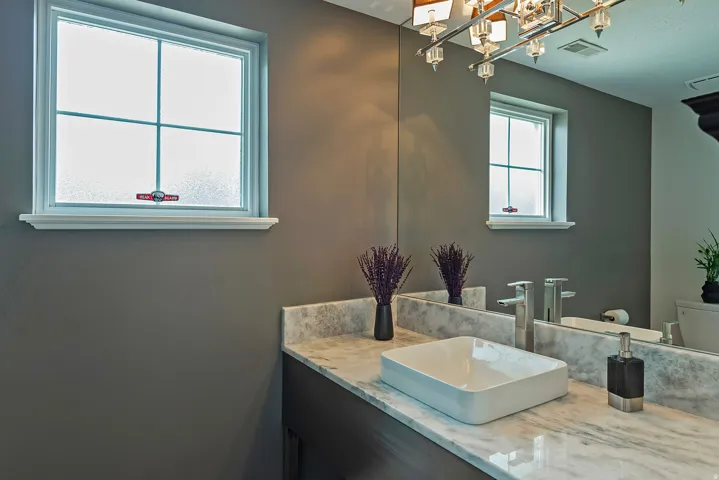 Contemporary bathroom featuring a rectangular vessel sink, polished chrome fixtures, and a marbled countertop