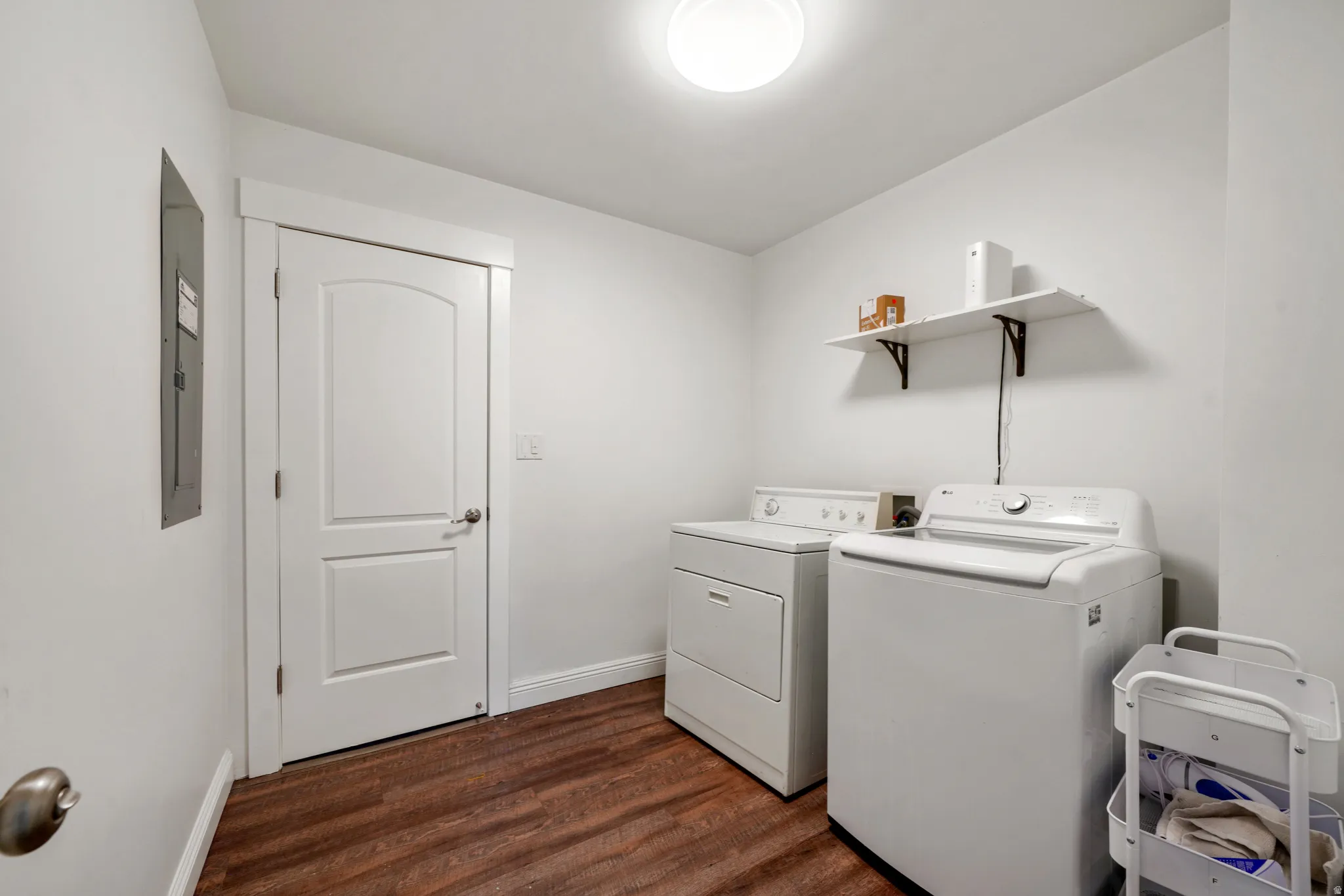 Dedicated utility space featuring wood-finish flooring, white walls, and a ceiling-mounted light fixture