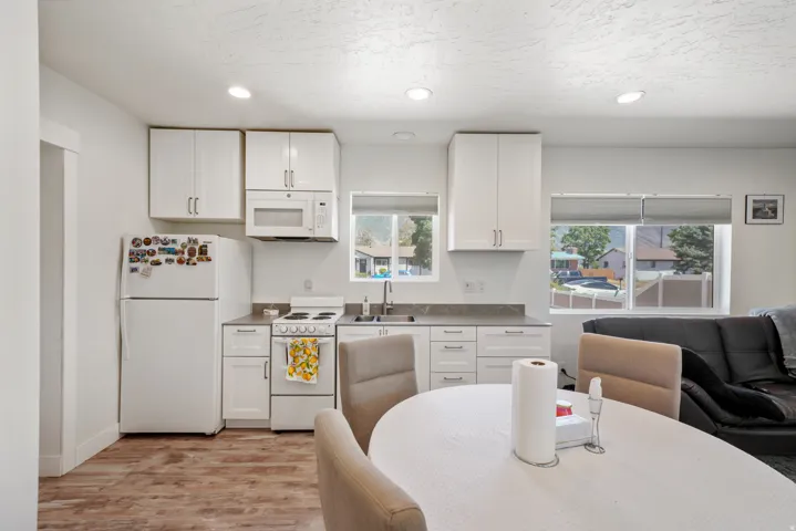 Kitchen featuring wood-finish flooring, white cabinetry, a built-in microwave, and a stainless steel sink with a window above