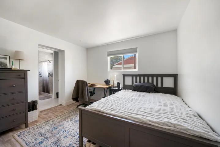 Bright interior room with wood-finish flooring and a window with roller shade