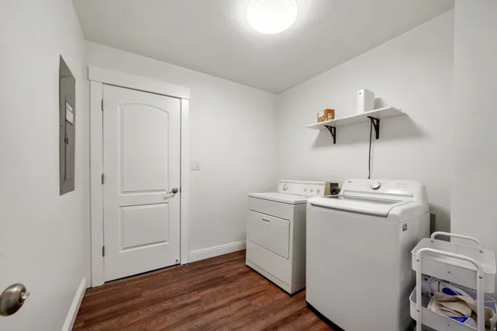 Dedicated utility space featuring wood-finish flooring, white walls, and a ceiling-mounted light fixture