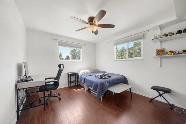 Bedroom featuring wood-finish flooring, white walls, and a ceiling fan with integrated lighting