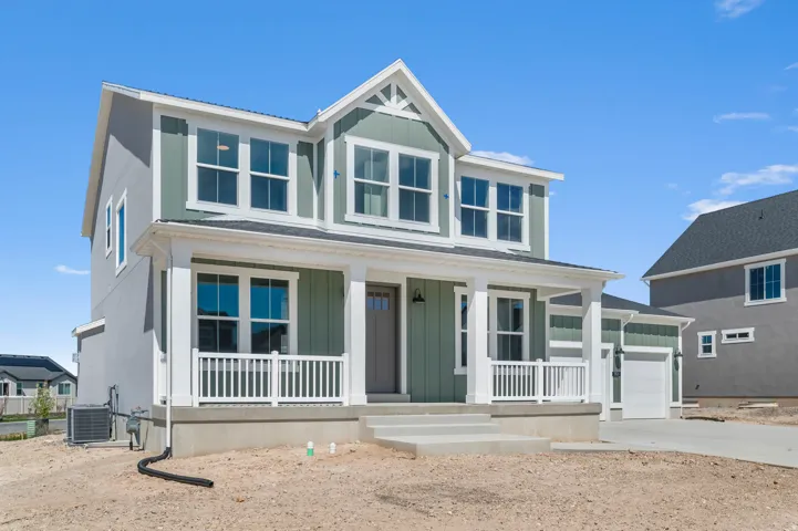 Two-story residence featuring a covered front porch with white railings, a light green siding facade, and white trim accents