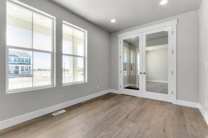 Spacious room featuring wood-finish flooring, light gray wall paint, and white trim
