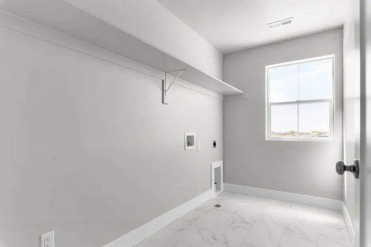 Utility room featuring a window, overhead shelving, tile flooring, and essential appliance hookups