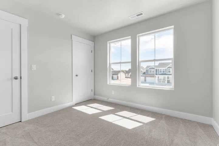 Carpeted room with two large windows, white trim, and light gray walls
