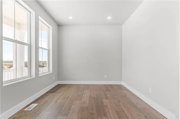 Bright interior space featuring two tall windows, recessed lighting, wood-finish flooring, and crisp white baseboards