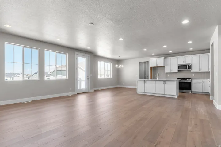 Spacious open-concept area featuring light wood-finish flooring, recessed lighting, and ample natural light from multiple windows