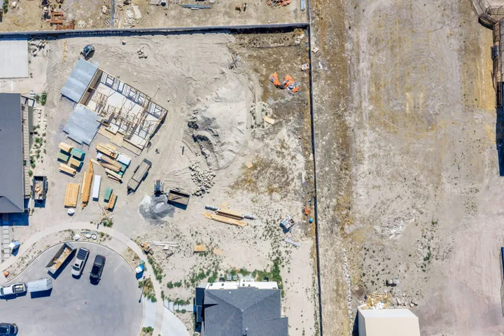 Developing residential lot featuring a partially framed structure, building materials, and surrounding dirt terrain